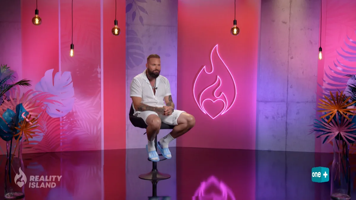 Ein Mann sitzt in einem Studio auf einem Stuhl.